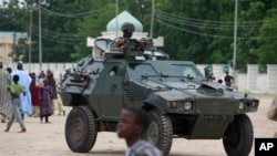 Nigerian soldiers ride on an armored personnel carrier in an area of Nigeria where an Islamic insurgency is raging, August 8, 2013.