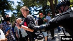 A police officer grabs a man antagonizing "anti-fascist" protestors after multiple people were stabbed during a clash between neo-Nazis holding a permitted rally and counter-protestors on Sunday at the state capitol in Sacramento, California, United State