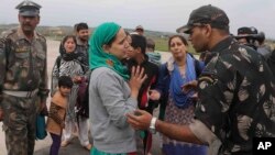 A Kashmiri flood victim, center, pleads to an Indian army officer to rescue her family members after she was airlifted by the army from her flooded neighborhood to the Indian Air Force base in Srinagar, Sept. 8, 2014. 