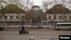 A motorcycle passes a closed-down warehouse in Yiwu, Zhejiang Province, China January 19, 2017. Picture taken January 19, 2017. 