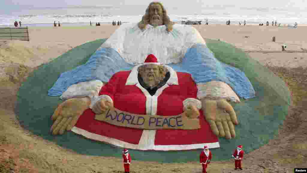 Des enfants habillés en Père Noël ont construit un géant statut de Père Noël et Jésus Christ avec sable accompagné de l&rsquo;artiste Sudarshan Pattnaik sur la plage de Puri dans l&rsquo;Est de l&rsquo;Etat indien Odisha, Ibde, 24 décembre 2014. &nbsp;
