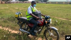 Yunusa Bawa, un agent de santé communautaire, circule sur une moto avec une boîte de vaccins contre le coronavirus d'AstraZeneca, à Sabon Kuje, dans la banlieue d'Abuja, au Nigeria, le 6 décembre 2021.
