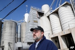 FILE - Matt Aultman, a grain salesman and feed nutritionist with Keller Grain & Feed, Inc., speaks beside grain and soybean silos at their facilities in Greenville, Ohio, April 5, 2018. Rural America is struggling under a cloud of uncertainty as the Trump administration escalates a trade dispute with China.