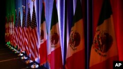 The flags of Canada, the U.S. and Mexico are lit by stage lights before a news conference at the start of NAFTA renegotiations in Washington, Aug. 16, 2017.