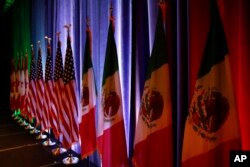 The flags of Canada, the U.S. and Mexico are lit by stage lights before a news conference at the start of NAFTA renegotiations in Washington, Aug. 16, 2017.