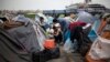 A man cuts another man's hair outside a passenger terminal used as a shelter for refugees and migrants at the Piraeus harbour in Athens on April 3, 2016. 