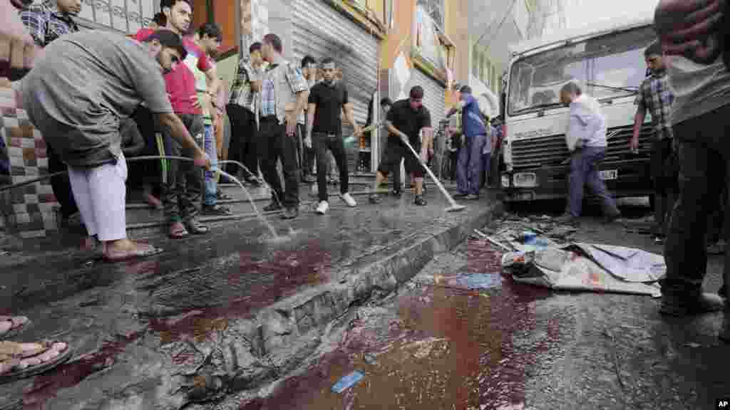 Palestinians wash blood from a sidewalk where seven Palestinians where killed in an Israeli air strike in Gaza City, July 12, 2014. 
