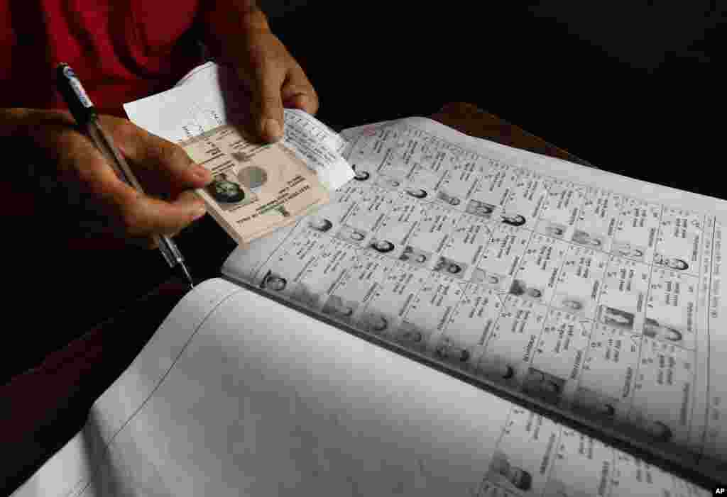 Um escrutinador verifica a identidade de um eleitor, na primeira fase das eleições em Agartala, no nordeste do Estado de Tripura, Índia, Abril 7, 2014.