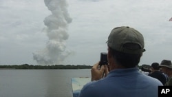 Stephen Bach, a landscape painter from Orlando, Florida, observes the plume left over from the final space shuttle launch in Cape Canaveral, Florida, July 8, 2011