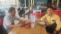 Feron Tololiu (40) dan Yobert Bolang (kanan, baju kuning) seusai menikmati hidangan di rumah makan yang menjual daging ular dan kelelawar di Desa Leilem, Minahasa, Sulawesi Utara, 12 Maret 2020. (Foto: Yoanes Litha/VOA)