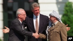 FILE - Israeli Prime Minister Yitzhak Rabin, left, and PLO chairman Yasser Arafat, right, shake hands as President Bill Clinton presides over the ceremony marking the signing of the 1993 peace accord between Israel and the Palestinians on the White House lawn.