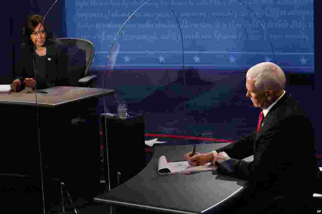 Vice President Mike Pence takes notes as Democratic vice presidential candidate Senator Kamala Harris answers a question during the vice presidential debate, held on October 7, 2020, at Kingsbury Hall on the campus of the University of Utah in Salt Lake City.