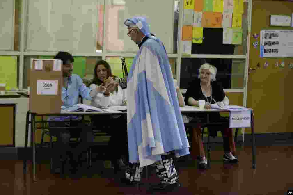 Seorang warga yang menggunakan jubah bendera Argentina menunjukkan KTPnya di TPS pada pemilu presiden di Buenos Aires.