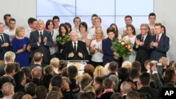 Conservative Law and Justice leader Jaroslaw Kaczynski, center left, and Justice candidate for the Prime Minister Beata Szydlo, center right, react at the party's headquarters in Warsaw, Poland, on Sunday, Oct. 25, 2015. 