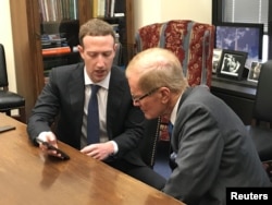 Facebook CEO Mark Zuckerberg holds a mobile phone while speaking with Senator Bill Nelson (D-FL) in the Hart Senate Office Building in Washington, April 9, 2018.