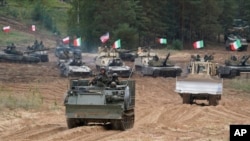 FILE - Military vehicles and tanks of Poland, Italy, Canada and the US participate in NATO military exercises in Kadaga, Latvia, Sept. 13, 2021.