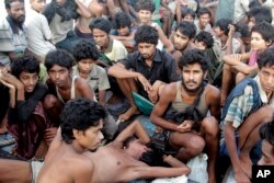 FILE- migrants including Myanmar's Rohingya Muslims sit on the deck of their boat as they wait to be rescued by Acehnese fishermen on the sea off East Aceh, Indonesia. Myanmar called sad and regrettable a move by the United States to place the country on a list of the world's worst human trafficking offenders.