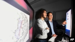 In this Friday, June 7, 2019 photo provided by the University of California at San Francisco, Dr Edward Chang, right, and postdoctoral researcher David Moses work on UCSF's Mission Bay campus.  (Noah Berger / UCSF via AP)