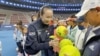 Chinese tennis player Peng Shuai signs large-sized tennis balls at the opening ceremony of Fila Kids Junior Tennis Challenger Final in Beijing, China, Nov. 21, 2021, in this screen grab obtained from a social media video. (Twitter @QINGQINGPARIS via Reute