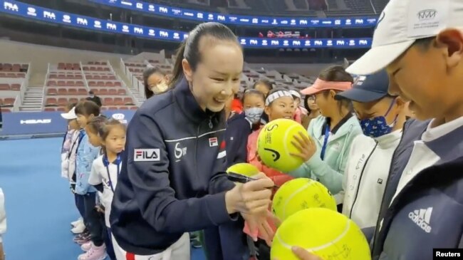 路透社11月21日从社交媒体上获取的照片。照片说明中说，彭帅在北京的Fila网球赛青少年选手决赛开幕式上在超大纪念网球上签名。