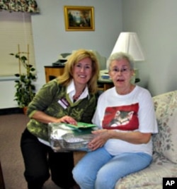 Home Instead's Kendra Kielbasa presents Kay Mamona with a Christmas gift