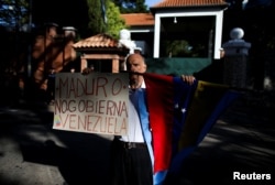 A Venezuelan demonstrator holds a banner that reads "[President Nicolas] Maduro doesn't govern Venezuela" outside the Olivos Presidential Residence, in Buenos Aires, Argentina, March 1, 2019.