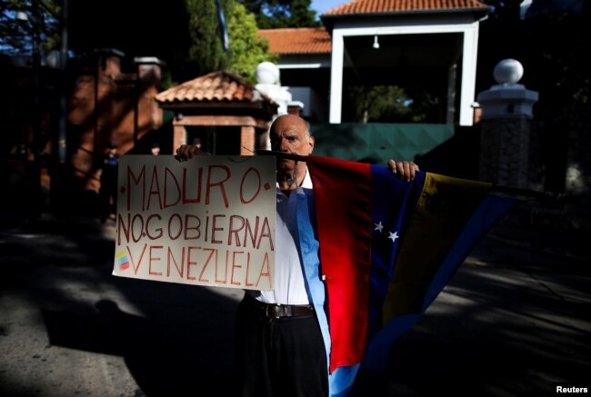 A Venezuelan demonstrator holds a banner that reads "[President Nicolas] Maduro doesn't govern Venezuela" outside the Olivos Presidential Residence, in Buenos Aires, Argentina, March 1, 2019.