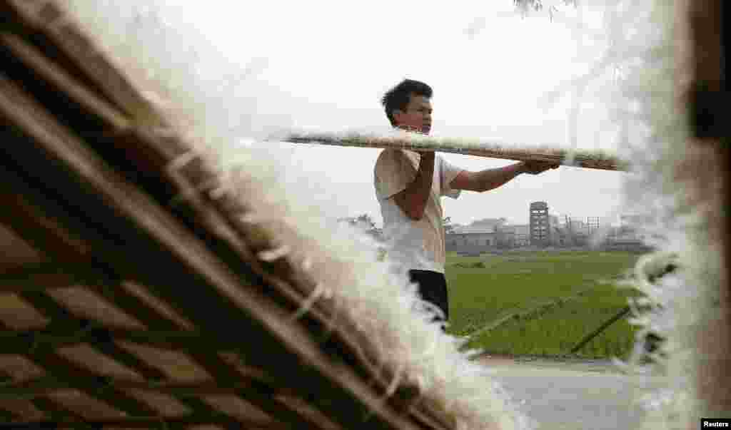 A man carries dried mien, or vermicelli made of cassava, after drying at Cat Que village outside Hanoi, Vietnam. Mien is used in several popular dishes containing chicken, beef, pork or seafood.