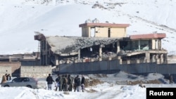 Afghan men stand in front of a collapsed building of a military base after a car bomb attack in Maidan Wardak, Afghanistan, Jan. 21, 2019. 