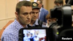 Russian opposition leader Alexei Navalny (L, front) is escorted by an Interior Ministry officer inside a courtroom in Kirov, July 18, 2013. 