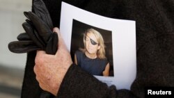 FILE - A man holds a sign honoring Sunday Times journalist Marie Colvin after a memorial service, outside St. Martin in the Field in London, May 16, 2012. 