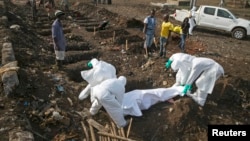 Health workers bury the body of a suspected Ebola victim at a cemetery in Freetown, Sierra Leone, Dec. 21, 2014. 