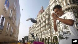 A man pays homage in front of portraits of police officers killed in the Mumbai terror attack outside the Taj Mahal Palace hotel, one of the sites of the attack, on the second anniversary of the attack in Mumbai, 26 Nov 2010