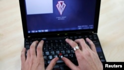 FILE - Romanian Razvan Cernaianu, formerly known as a hacker by the name of TinKode, works at his laptop in his office in Bucharest in this March 15, 2013 picture. 