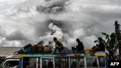 FILE - Indonesian bus passengers watch as Mount Sinabung spews thick smoke in Karo, North Sumatra, Jan. 2, 2018.