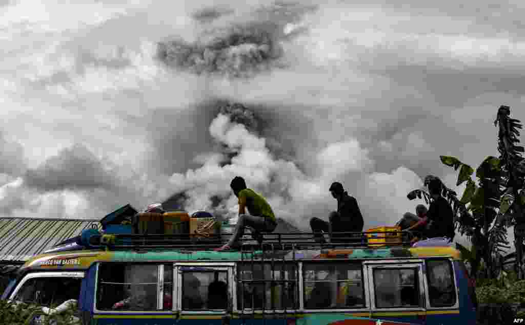 Penumpang bus melihat ke arah Gunung Sinabung yang mengeluarkan asap tebal di Kabupaten Karo, Sumatra Utara.