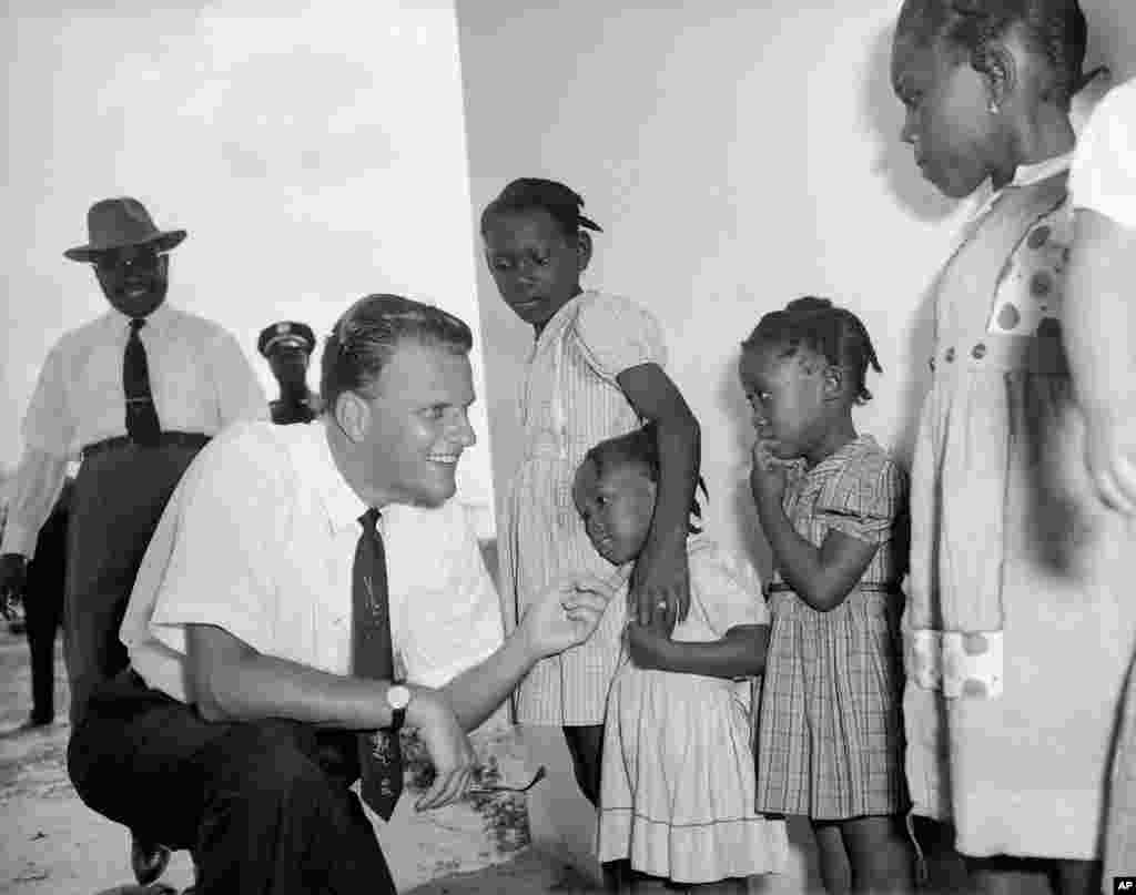 L'évangéliste Billy Graham salue des jeunes filles lors d'une visite à un institut missionnaire à Virginia, au Libéria, le 20 janvier 1960.