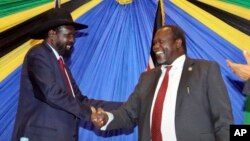 FILE - South Sudan's President Salva Kiir, left, shakes hands with rebel leader and former vice president Riek Machar after signing an agreement to reunify their political party in Arusha, Tanzania, Jan. 21, 2015.