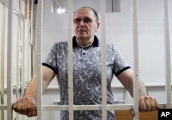 FILE - Oyub Titiev, head of the Memorial Human Rights Center in Chechnya, stands behind bars in court before a hearing in Chechya's provincial capital Grozny, Russia, July 18, 2018.