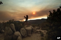 Mara Schumann photographs a plume of smoke from the Ferguson Fire in Yosemite National Park, Calif., July 24, 2018. Parts of the park, including Yosemite Valley, closed as firefighters worked to stop the blaze.