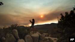 Mara Schumann photographs a plume of smoke from the Ferguson Fire in Yosemite National Park, Calif., July 24, 2018. Parts of the park, including Yosemite Valley, closed as firefighters worked to stop the blaze.