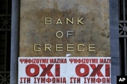 Posters reading "We vote en masse, no the agreement'' are seen under Bank of Greece logo in Athens, July 3, 2015.
