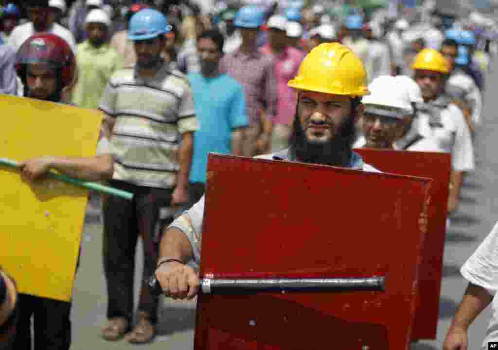 Supporters of Egypt&#39;s Islamist President Mohamed Morsi hold sticks and wear protective gear outside of the Rabia el-Adawiya mosque near the presidential palace, in Cairo, Tuesday, July 2, 2013. 