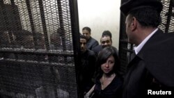 FILE - Activists, accused of working for unlicensed non-governmental organizations (NGOs) and receiving illegal foreign funds, stand in a cage during the opening of their trial in Cairo, March 8, 2012. Egypt's parliament approved a bill to regulate non-government organizations November 15. 