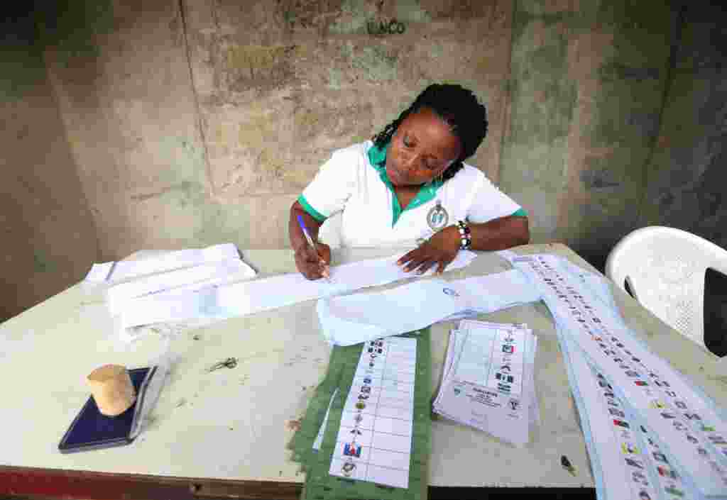 یک مقام انتخاباتی روی ورقه های رای در اویو، نیجریه یادداشت بر می دارد. نیجریه رای گیری را برای انتخاب فرمانداران ایالتی آغاز کرد. 26 آوريل 2011 (AP)