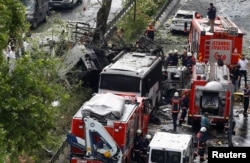 FILE - Forensic experts and firefighters stand beside a Turkish police bus which was targeted in a bomb attack in a central Istanbul district, Turkey, June 7, 2016.