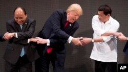 El presidente Trump parece enredarse en el apretón de manos "tradicional" de la cumbre: un ejercicio en el que cada líder pasa su brazo derecho sobre el izquierdo para dar la mano contraria a quien está a su lado.