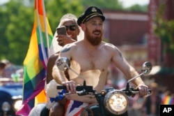 Scott Simpson, foreground, and his husband, Michael Clarke, ride with the Out Riders Women's Motorcycle Club, going as Prince Harry and Meghan Markle, in the Capital Pride Parade in Washington, June 9, 2018.