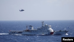 FILE - A Chinese ship and helicopter are seen during a search and rescue exercise near the Qilian Yu subgroup in the Paracel Islands, which is known in China as Xisha Islands, South China Sea, July 14, 2016.