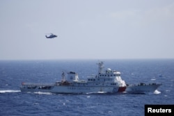 FILE - Chinese ship and helicopter are seen during a search and rescue exercise near Qilian Yu subgroup in the Paracel Islands, which is known in China as Xisha Islands, South China Sea, July 14, 2016.